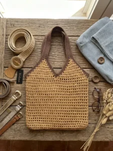Bolso de rafia tejida con asas marrones sobre madera